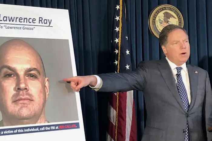 U.S. Attorney Geoffrey Berman points to a photo showing Lawrence Ray during a news conference, in New York. Ray, an ex-convict known for his role in a scandal involving former New York police commissioner Bernard Kerik, was charged Tuesday with federal extortion and sex trafficking charges involving a group of students at Sarah Lawrence College